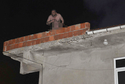 Evini yakıp, çıplak halde çatıya çıktı