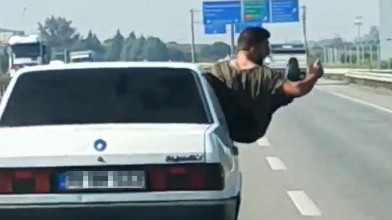 Bursa’da trafikte tehlikeli hareketler Bursa'da, otomobilin ön yolcu koltuğunun penceresine çıkıp, oturan ve bir