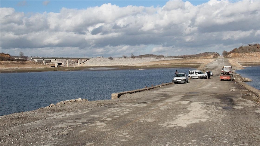 Barajdaki su seviyesi düşünce ortaya çıkan eski yoldan olta atıp balık avlıyorlar