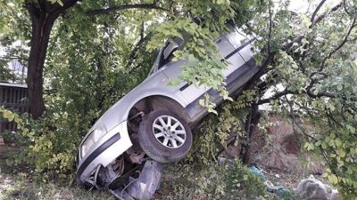 Kaza yapan otomobil ağaçta asılı kaldı